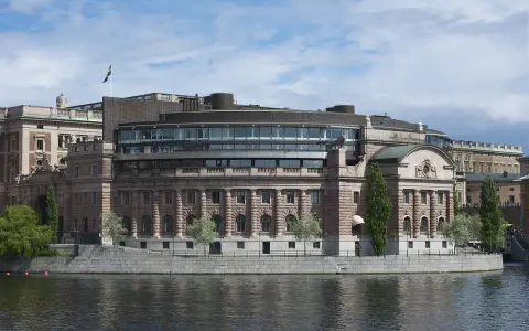 Riksdagshuset i Stockholm, en symbol för sveriges statsskick, med sin moderna glasdel och klassiska stenfasad vid vattnet.