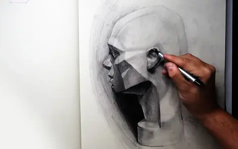 Un artista trabaja en dibujos difíciles a lápiz de un rostro geométrico, capturando la luz y la sombra con gran detalle.