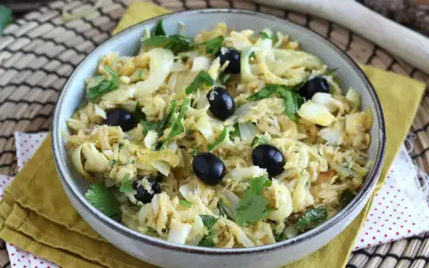 Delicioso bacalao a bras, desmenuzado con patatas finas, huevo y aceitunas negras, adornado con perejil fresco.