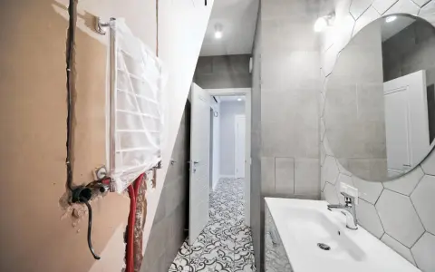 Bagno in ristrutturazione con impianto idraulico a vista, pronto per la detrazione 65. Pavimento decorato e lavabo moderno.
