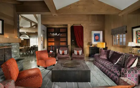 Arredare taverna con stile: divani viola, poltrone arancioni e un grande tavolino centrale in legno.