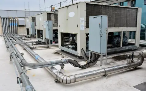Unidades de aire acondicionado industriales en una azotea, con tuberías de ventilación y aire acondicionado (HVAC) conectadas.