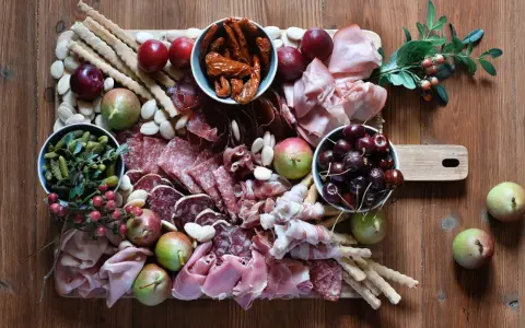 Un invitante tagliere fai da te con salumi, formaggi, frutta, sottaceti e grissini, pronto per essere gustato.
