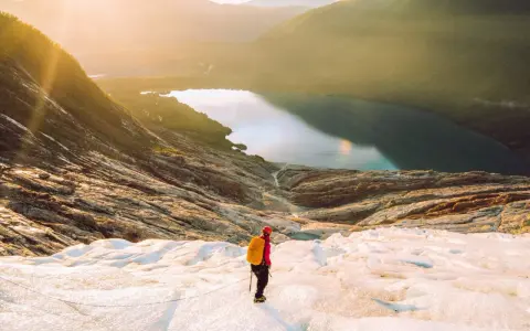 Vandrare på en glaciär i Norge med en sjö och berg i bakgrunden. En av många norge sevärdheter.