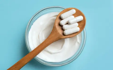 Cuillère en bois avec des gélules blanches sur un yaourt crémeux. Une question se pose : quel probiotique pour maigrir ?