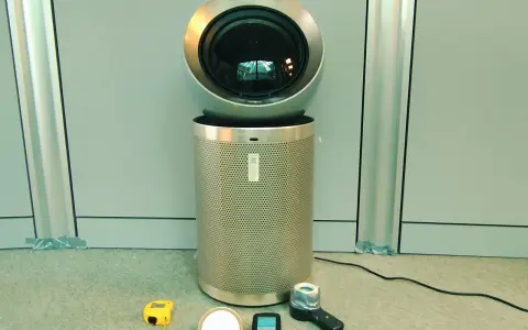 Nowoczesne oczyszczarki powietrza i sprzęt pomiarowy. Urządzenie z okrągłą górą i perforowanym cylindrem, obok taśma miernicza, miernik i inne akcesoria.