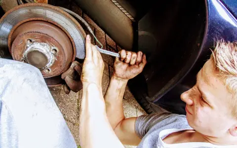 Ragazzo con mani sporche lavora sul freno, forse per un cuscinetto ruota rotto sintomi.
