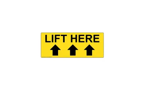 Żółty znak z napisem "LIFT HERE" i trzema czarnymi strzałkami skierowanymi w górę. To jasny znak tu chwytać, by podnieść przedmiot.