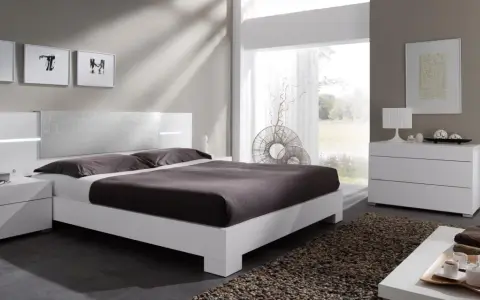 Habitación con muebles blancos y color pared neutro. Cama moderna, mesitas de noche, cómoda y espejo.