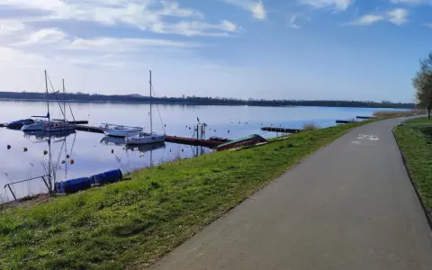 Jezioro Pogoria 4 z łodziami przy pomoście i ścieżką rowerową.