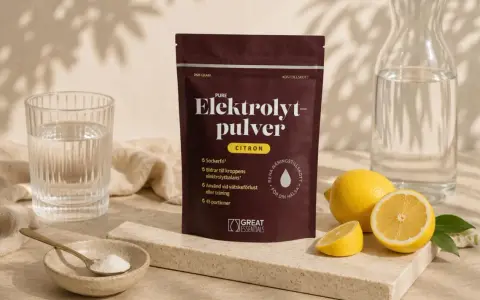 En påse elektrolytpulver med citronsmak, bredvid färska citroner, ett glas vatten och en skål med pulver. Selen finns i för att återställa vätskebalansen.