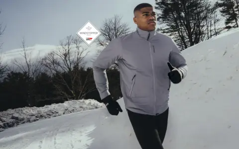Läufer im Schnee, geschützt durch GORE-TEX INFINIUM™ WINDSTOPPER® Jacke und Handschuhe.