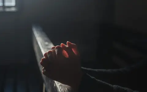 Dłonie złożone w modlitwie w ciemności, szukające nadziei. Modlitwa w sprawach trudnych i beznadziejnych do św. Józefa.
