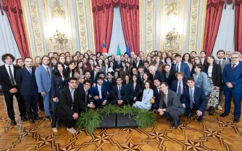 Un folto gruppo di giovani studenti posa per una foto di gruppo, forse dopo un evento alla scuola di giornalismo Roma.