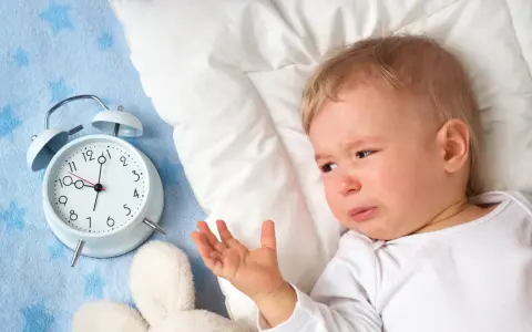Płacz 1,5 rocznego dziecka, które nie chce spać w dzień. Obok budzik i pluszaki.