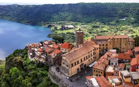 Nemi, un borgo incantevole a breve distanza da Roma, si affaccia sul lago. Case con tetti rossi si aggrappano alla collina, circondate da verde lussureggiante.