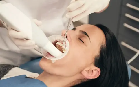 Dentysta bada zęby pacjentki, która używa specjalnej pasty na ruszające się zęby.