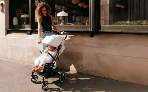 Kobieta prowadzi dziecko w wózku Cybex Beezy ulicą.
