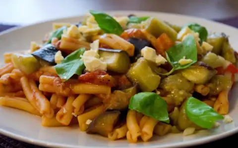 Pyszne danie z makaronem, bakłażanem i pomidorami, posypane serem i bazylią. Idealne na Pasta alla Norma przepis.