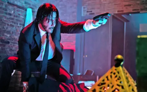 John Wick i svart kostym, med pistol i hand, redo för strid. Kanske en scen från John Wick 5.