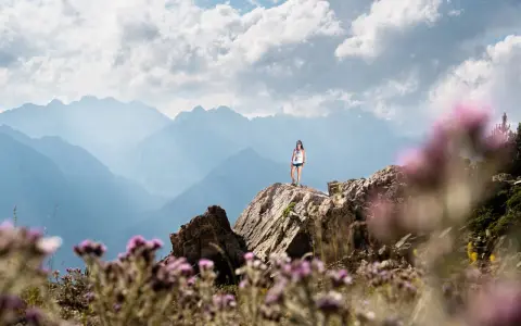 Una mujer en la cima de una montaña rocosa, disfrutando de las vistas. ¡Una gran idea de qué hacer en Cerler en verano!