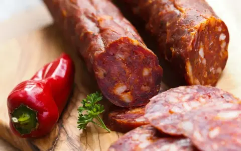 Kawałki pikantnego chorizo, czerwona papryczka i natka pietruszki na desce. Chorizo co to? To aromatyczna kiełbasa!