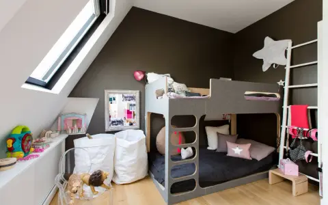 Accogliente camera da letto e cameretta insieme, con letto a castello grigio, giocattoli, cuscini a forma di stella e sacchi bianchi.
