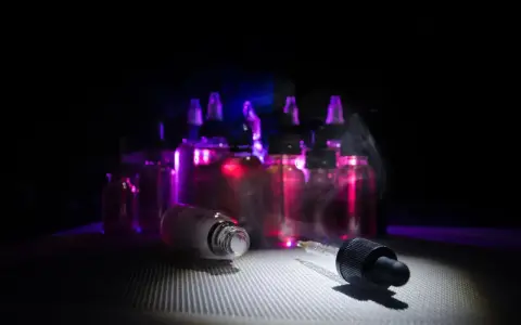 Gotas de nicokit como usar: frascos de líquido para vapear con luz púrpura y vapor.