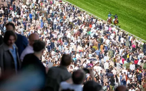 Foule nombreuse sur un hippodrome en France, spectateurs massés pour une course de chevaux.