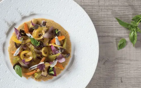 Socca garnie de légumes colorés et d'anchois, une idée pour votre recette socca.