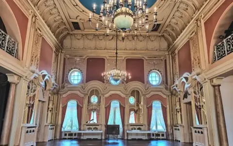 Wnętrze pałacu w Poznaniu, idealne do zwiedzania. Bogato zdobiony sufit, kryształowe żyrandole i eleganckie zasłony tworzą atmosferę dawnej świetności.