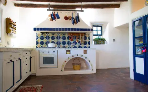 Cocina rústica con azulejos coloridos y detalles DIY, ideal para decorar casa de campo con poco dinero. Cestas y ollas cuelgan, creando un ambiente acogedor.