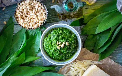 Pesto z czosnku niedźwiedziego, orzechów pinii i oliwy. Obok kawałek sera, który może być alternatywą, jaki ser do pesto zamiast parmezanu?