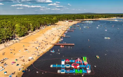 Słoneczny dzień na zalewach świętokrzyskich. Tłumy plażowiczów, wodne atrakcje i mnóstwo łódek na tafli wody.