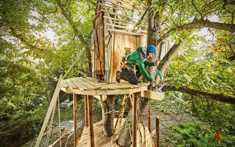 Mann baut Baumhaus für Kinder. Tolle baumhaus kinder ideen für Abenteuer im Grünen.