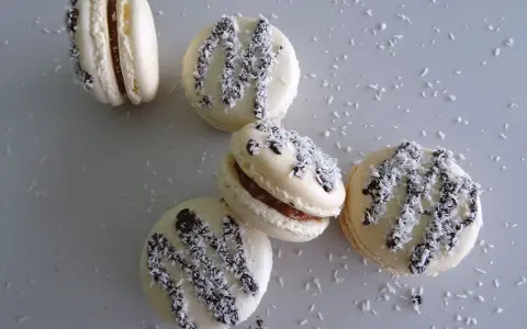Macarons à la ganache coco, parsemés de noix de coco râpée et de copeaux de chocolat noir.