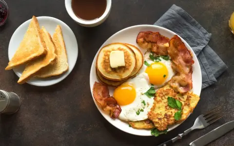 Esempio di colazione proteica per dimagrire: uova, bacon, pancake, toast e succo d'arancia.