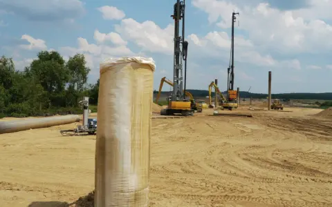 Construcción en terreno arenoso, con maquinaria pesada y tuberías. Se aprecian varios tipos de suelos blandos, listos para la obra.