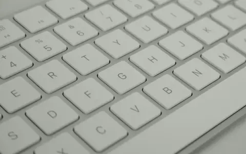 Zbliżenie na klawiaturę komputerową. Widoczne klawisze z literami: E, R, T, Y, U, I, O, P, A, S, D, F, G, H, J, K, L, Z, X, C, V, B, N, M. Opis klawiszy.