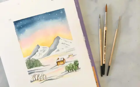 Une aquarelle montagne facile dépeint un paysage hivernal doux avec des montagnes enneigées, des chalets chaleureux et un ciel étoilé. Trois pinceaux sont posés à côté.