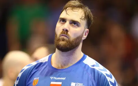 Andreas Wolf, zamyślony zawodnik w niebieskiej koszulce z herbem Kielc, patrzy w górę.