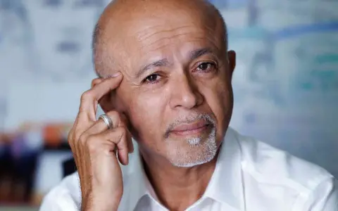 Ritratto di Abraham Verghese, con la mano sulla tempia, pensieroso.