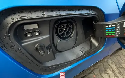 Gniazdo ładowania w niebieskim samochodzie. To pokazuje, co to jest plug-in hybrid – samochód, który można ładować z sieci.