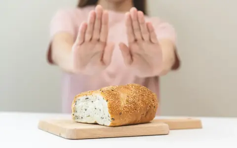 Osoba odrzuca chleb, sygnalizując uczulenie na gluten i laktozę objawy.