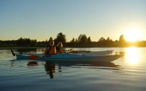 Två kvinnor i kajak njuter av solnedgången vid en sjö nära Karlstad.