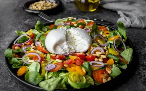 Frischer Salat mit Burrata, Tomaten, Zwiebeln und Pinienkernen. Perfekt für eine leichte Mahlzeit, auch in der Schwangerschaft.