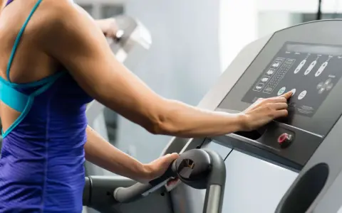 Frau stellt Steigung für ihr **incline walking** auf dem Laufband ein.