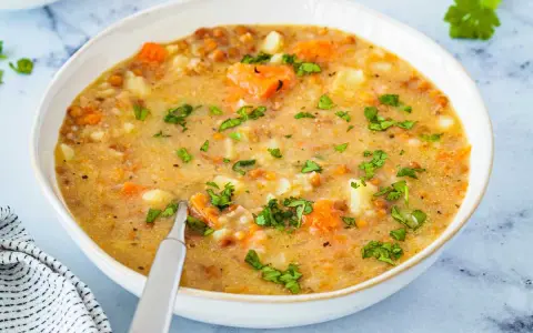 Un tazón de sopa de lentejas casera con zanahorias y patatas, perfecto para aprender como hacer lentejas.