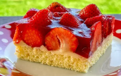 Ein saftiges Stück Erdbeerkuchen vom Blech, belegt mit frischen Erdbeeren und Tortenguss.