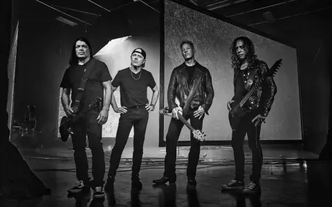 James Hetfield und Metallica im Jahr 2000, bereit für die Bühne. Die Bandmitglieder stehen in dunkler Kleidung, einige mit Gitarren.